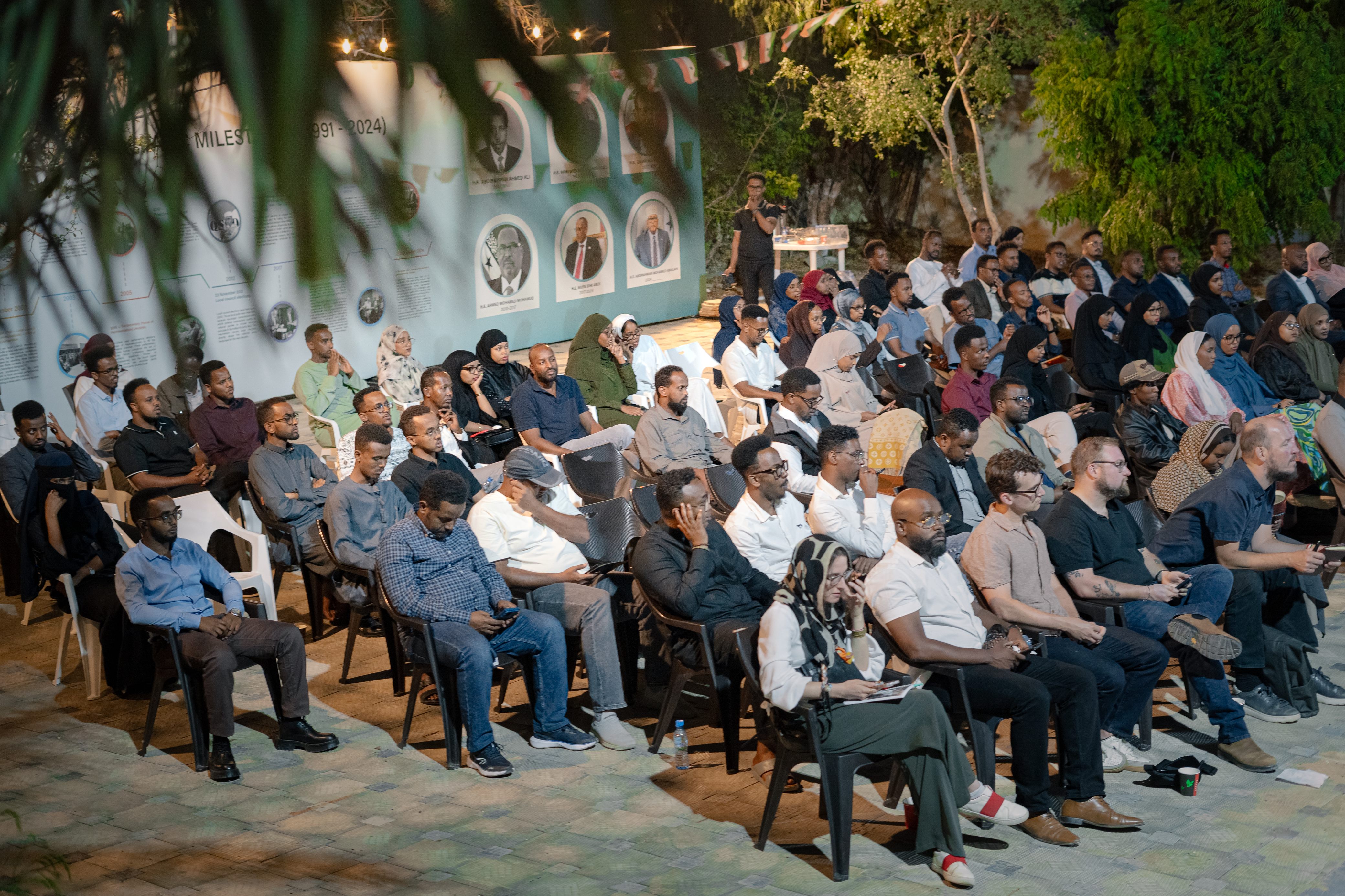 A diverse audience attending an evening public forum